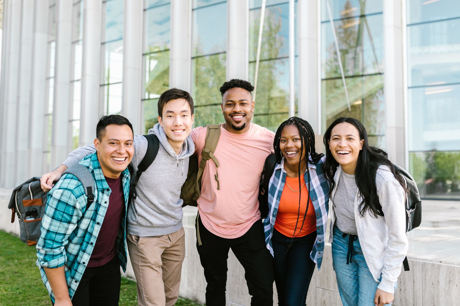 A diverse group of young adults smiling together outdoors.