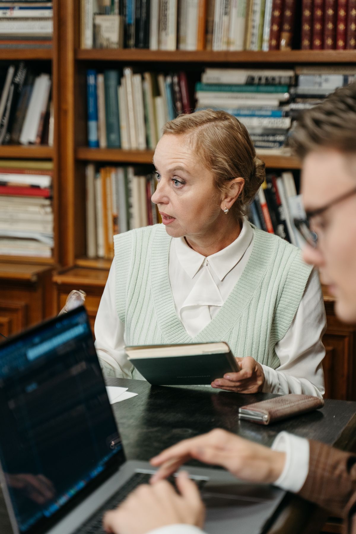 A researcher and a student talking in a library.